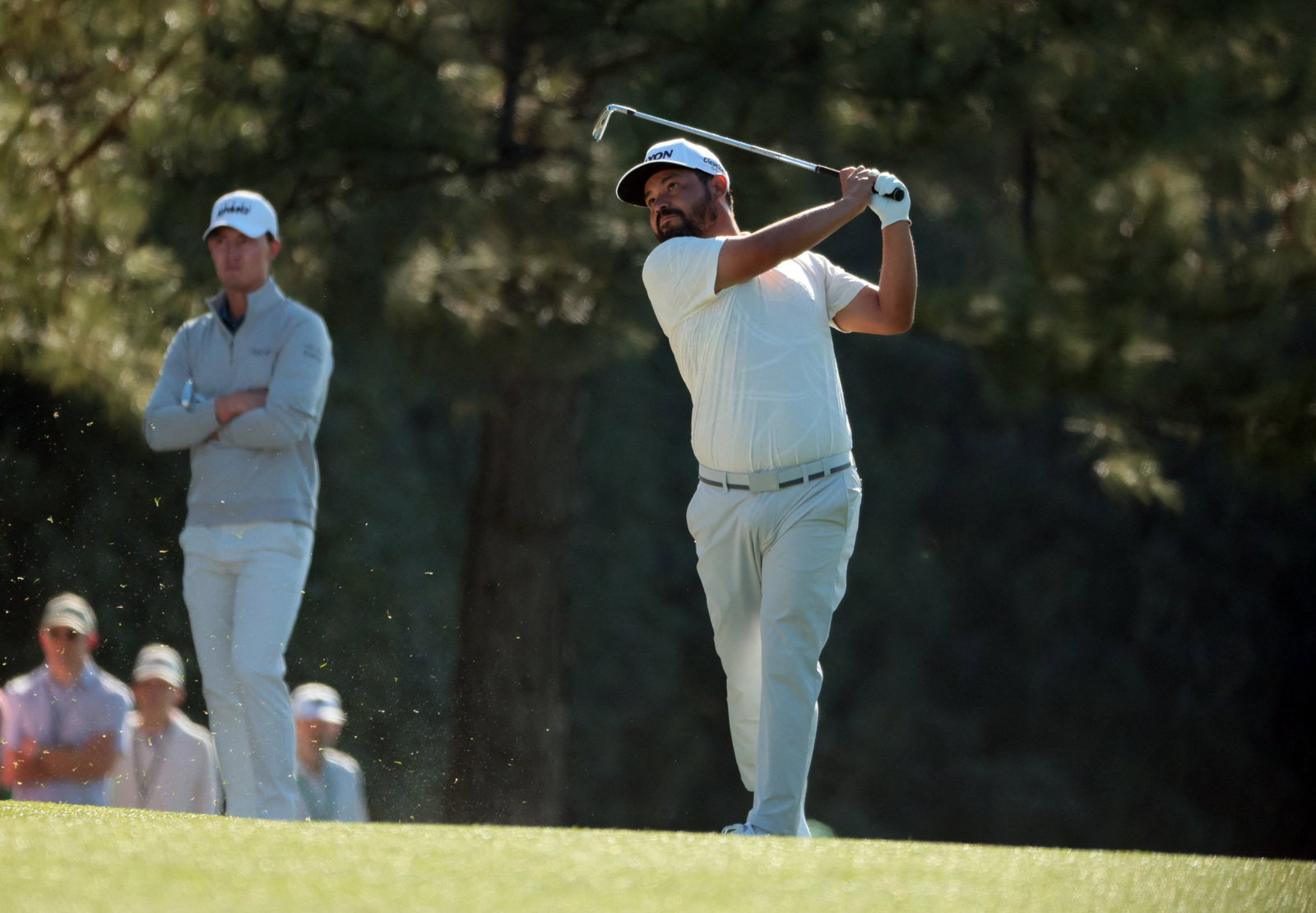 Spaun plays an approach shot as McNealy watches on